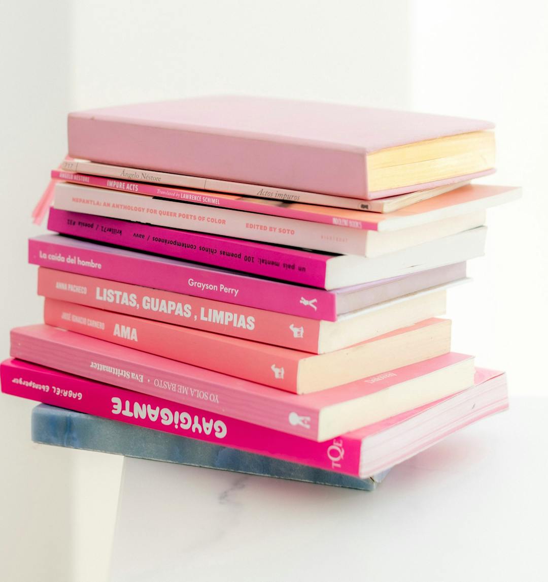 Bunke med rosa/røde bøker på et hvitt bord.